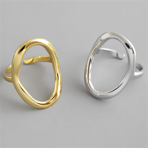Two chunky, organic-shaped open rings, one gold and one silver, shown side by side.