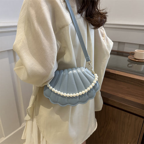 Light blue faux leather shell-shaped shoulder bag with a pearl strap and matching thin strap.