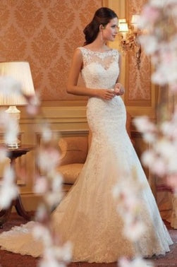 White lace mermaid wedding dress with sleeveless illusion neckline worn by a model.