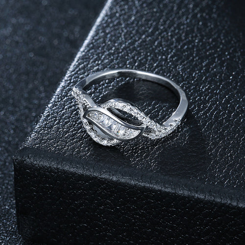 Silver ring with sparkling stones in a leaf-like intertwined design resting on a black box.
