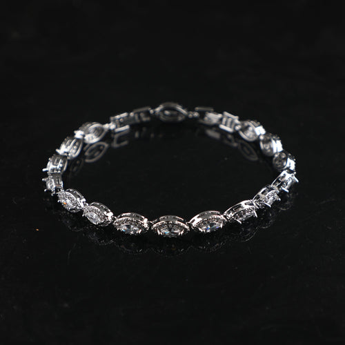Silver bracelet featuring linked eye-shaped charms with sparkling crystals on a black surface.