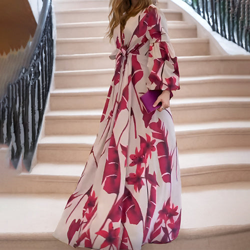 A woman in a cream dress with large red floral prints, standing on a staircase.