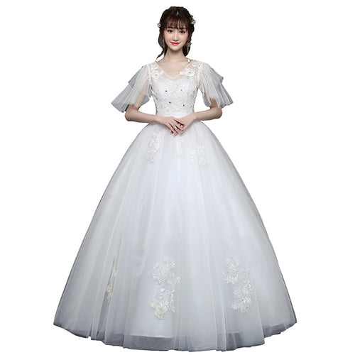 A model in a white tulle wedding dress with layered flutter sleeves, V-neckline, and floral lace appliqués.