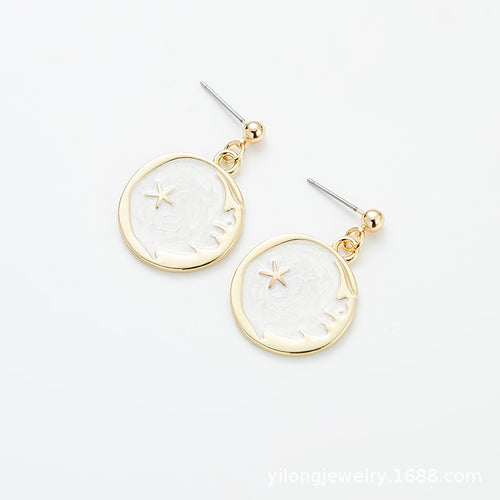 Gold-rimmed round earrings featuring a white crescent moon and a star motif against a marbled background.
