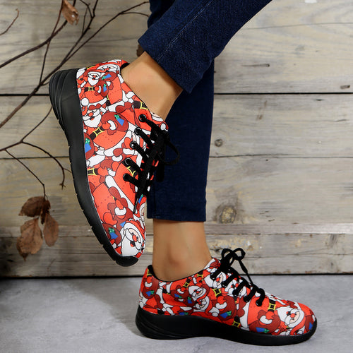 Red sneakers with festive Santa Claus print, black laces, and black soles, worn with blue jeans.