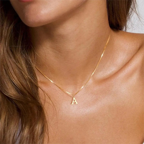 Thin gold chain necklace with letter A pendant worn on a person's neck.