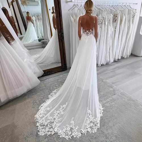 White satin and lace wedding dress with thin straps, a low back, and a long flowing train.