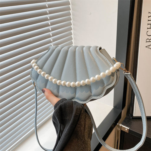 Light blue faux leather shell-shaped shoulder bag with a faux pearl handle and thin strap.