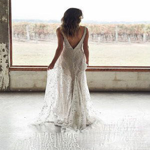 Woman from behind wearing a bronze-colored V-neck long dress with a sparkling, sheer overlay.