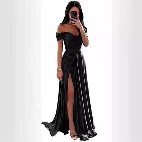 A woman wearing a long, off-the-shoulder black satin evening dress with a high leg slit.