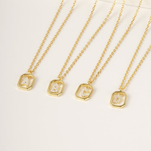 Four gold-toned chain necklaces featuring rectangular pendant frames with letters A, B, C, and D inset with small stones.